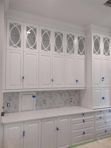 Floor-to-ceiling white cabinetry with glass-front uppers and a mosaic marble backsplash for a fresh, classic kitchen look