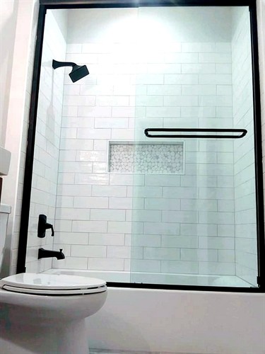 Classic white subway tile, a tiled niche accent, and matte black hardware create a clean, modern shower design