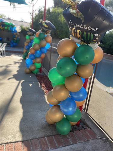 Graduation Balloon Tower made with 12" Helium quality Metallic Finish Balloons offered by Party Over Here in Green, Blue and Gold colors.