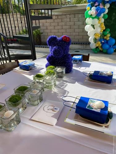 Tablescape made with custom rose covered teddy bear made with bling artificial flowers in celebrants favorite color.
