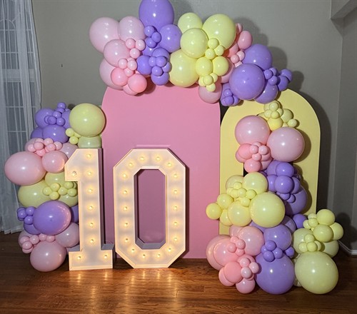 Pastel balloon backdrop with marquee numbers for a stylish 10th birthday celebration.