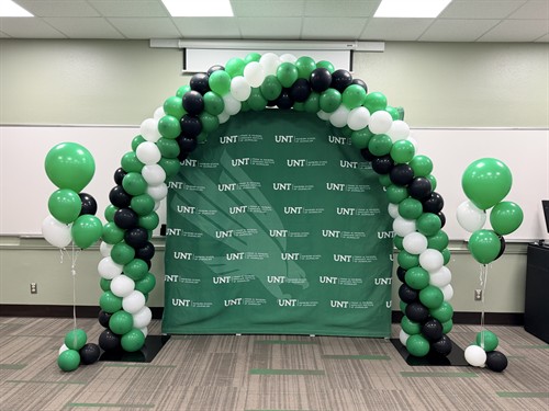 Green, white, and black balloon arch for a University of North Texas event.
