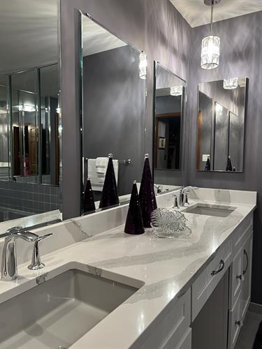 Master Bathroom features deep purple walls as the backdrop to gorgeous white and gray countertop with gray sink. Don't let boring white sinks be your only options. Exquisite lights are the sparkling jewels.