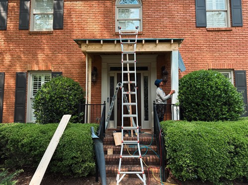 Recommended Alt Text "A custom front door portico under construction with white columns and a gabled roof, built by Hoover Deck & Porch to add curb appeal.