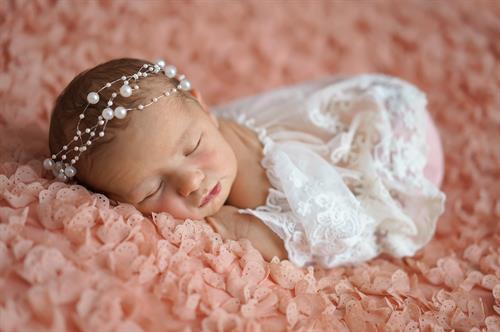 Little Dreamer – newborn girl resting on soft pink.