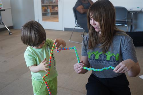 A Parent Coach plays with a toddler during a playgroup at the Public Library.