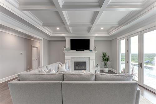 Coffered ceiling is featured in the all-white living room