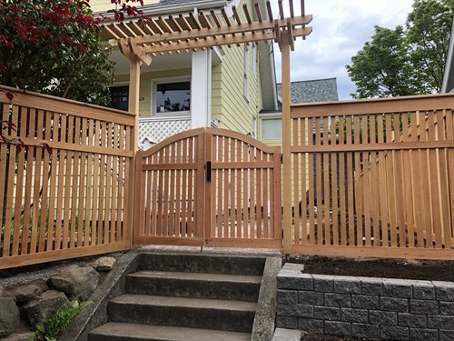 Handcrafted cedar fencing with a custom gate and pergola entryway