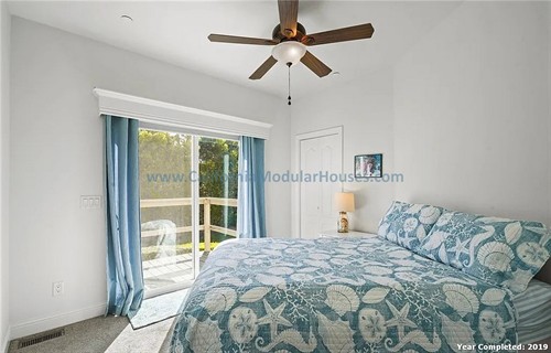 Bedroom with white walls, a sliding glass door leading to a porch, a ceiling fan.  California Modular Houses. Pre fabricated homes.  Modular houses for California.  Casas modulares.  Coastal California.  Ventura County, CA.  