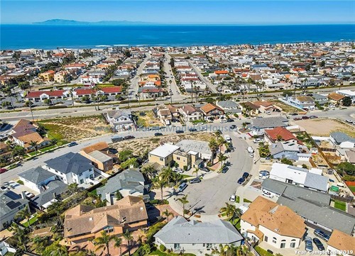 Aerial view of a coastal residential neighborhood with houses, streets, palm trees, and the ocean in the background.   California Modular Houses. Modular home construction California.  Prefab house.  Oxnard, Ventura County, CA.  