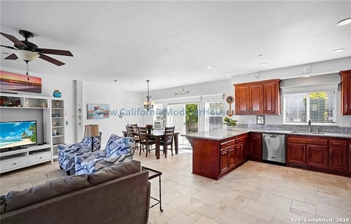 Open-concept living room and kitchen with white walls, tile flooring, wooden cabinets.  California Modular Houses. Pre fab home.  Modular homes for California.  Casas prefabricadas.  Southern California.  