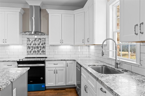 Modern Kitchen featuring crisp whiote shaker-style cabinetry, elegant gray countertops whith stainless steel finishes