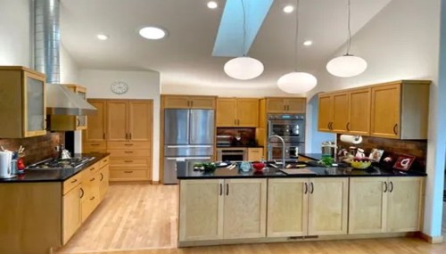 Custom kitchen remodel by Alderwood Builders LLC in Bellingham, WA featuring natural wood cabinetry, a large center island, skylight, and modern lighting designed for functionality and style.