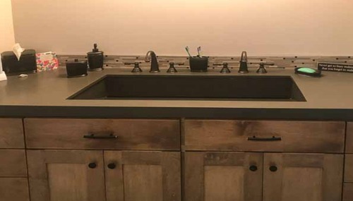 Custom bathroom vanity with solid surface countertop and matte black sink by NW Granite & Flooring.
