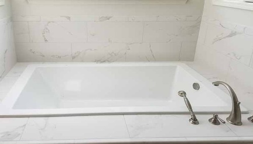 Marble-look tile bathtub surround and custom bathroom finish completed by NW Granite & Flooring.