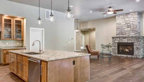 Open-concept kitchen featuring custom natural stone countertops and island by NW Granite & Flooring.