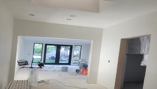 Commercial drywall installation in Washington home showing freshly finished walls, ceiling work, and construction equipment.