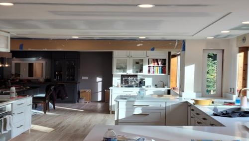 Interior drywall repair in progress with patching tools and equipment used for fixing door-knob holes and wall damage.