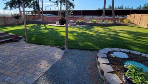 Professional backyard landscape design with lush green lawn and patio installation by Three Men and a Mower.