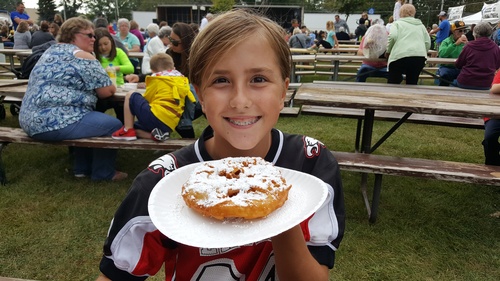 Child holding a deep fried treat on a plate at Cow Chip