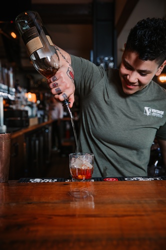 Bartender pouring an old fashioned at Vintage Brewing Co