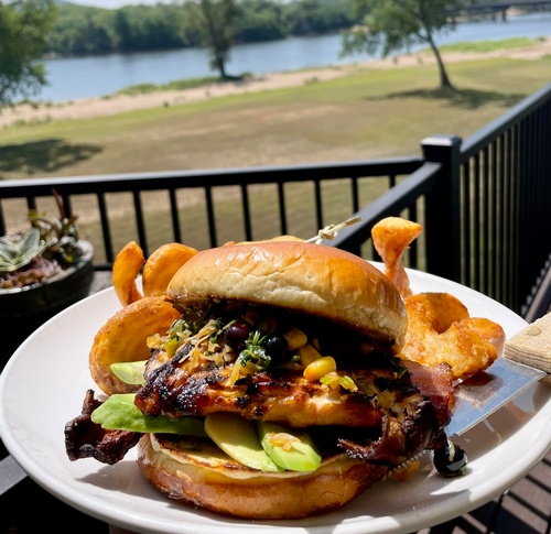 Chicken sandwich with fries on outdoor patio at Vintage Brewing Co