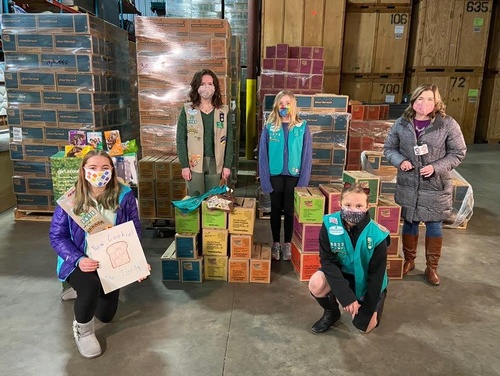 girl scouts in front of cookie boxes