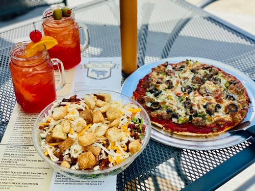 salad, pizza, and drinks at outdoor table