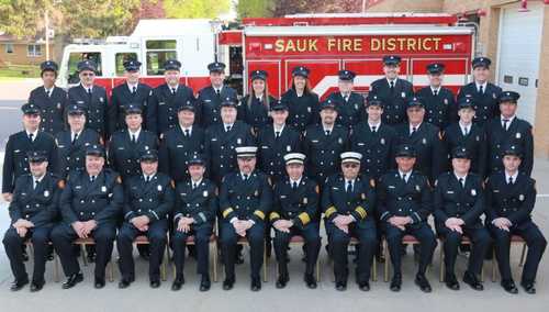 Firefighter members posed in uniform in front of the fire truck