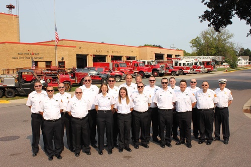 Firefighter members posed in uniform on the street in front of the fire department