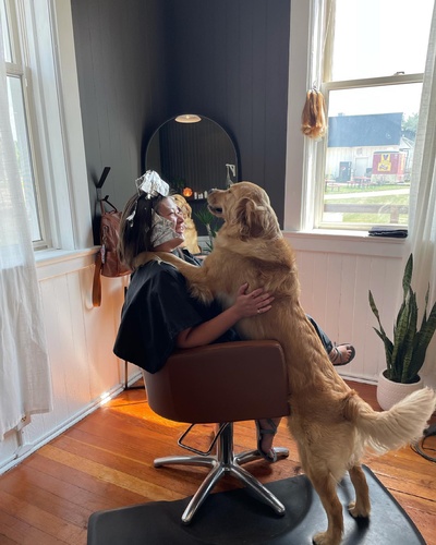 Women petting dog while getting hair done