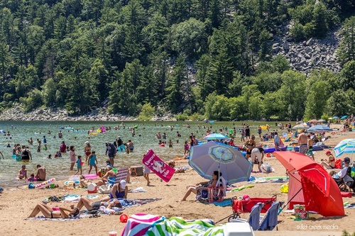 People sitting on the beach and in the water at Devil's Lake state park