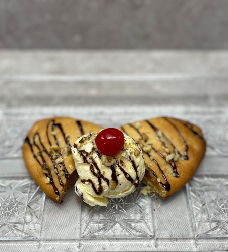 Sweet Potato Empanada topped with a scoop of vanilla ice cream, chocolate drizzle, walnuts, and a cherry. 