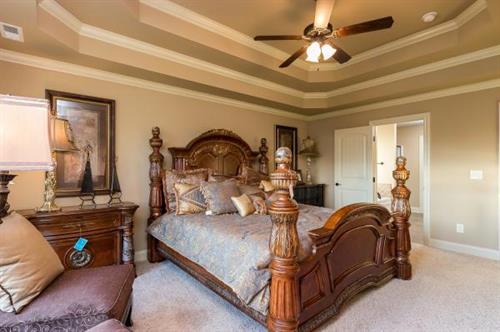 Inviting Master Bedrooms with tiered ceilings and warm lighting.