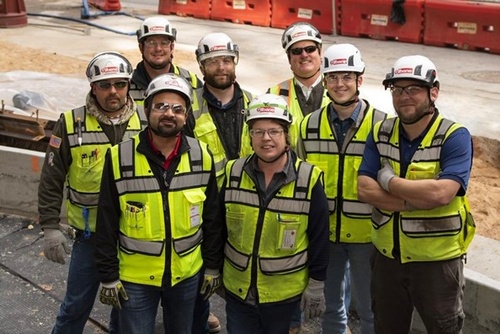 Gilbane Building Company team smiling, standing together onsite, in uniform for a group photo. 