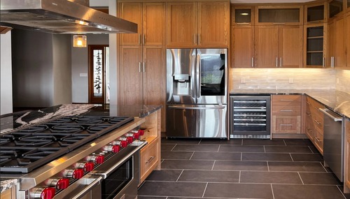 Luxury custom kitchen with walnut cabinetry, professional gas range, and stone countertops in an Anacortes custom home.